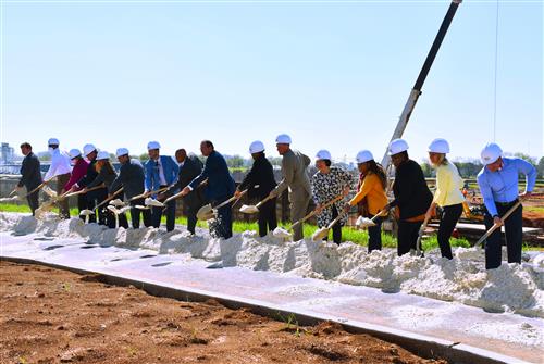 17 leaders lined up with shovels and construction crane in background 